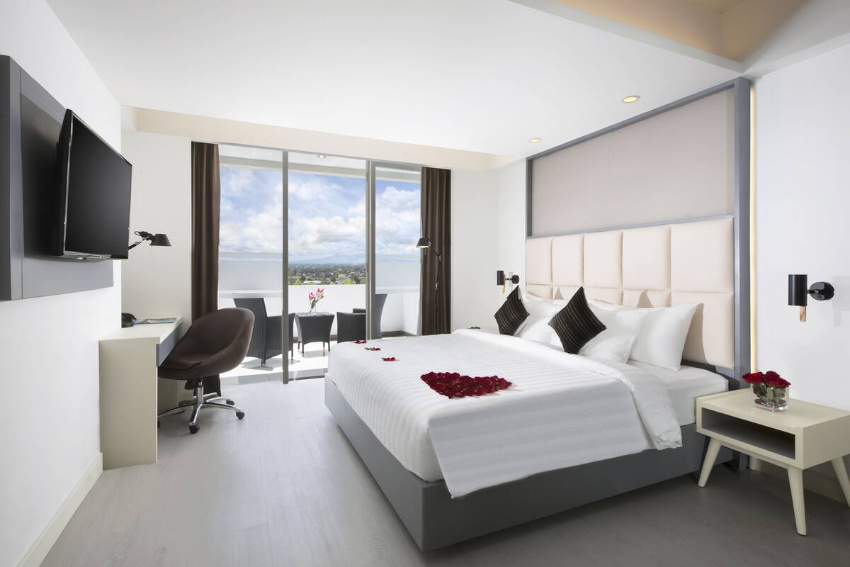 Une chambre d’hôtel moderne, dotée d’un grand lit, d’un bureau et d’une télévision.