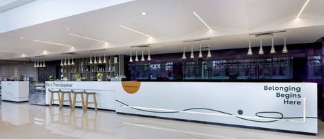 A modern, well-lit reception area with a counter, bar stools, and a glass display case.