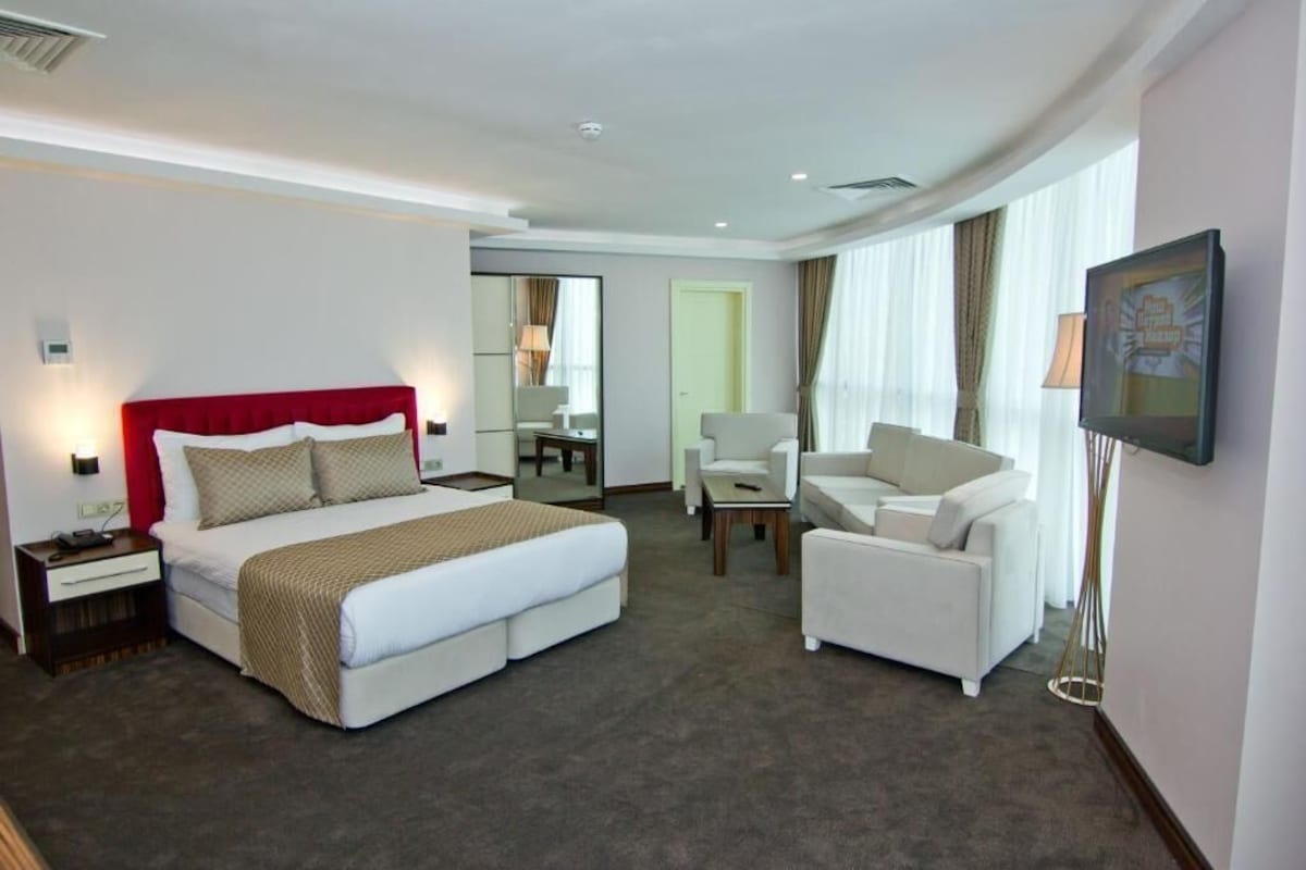 A hotel room with a bed, a desk, a chair, and a TV.