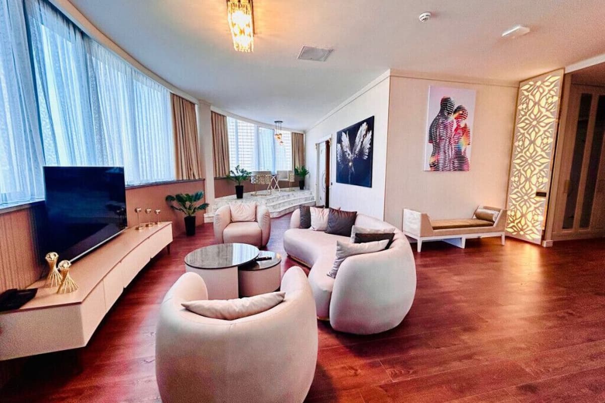 A modern living room with a flat-screen TV, a sofa set, a coffee table, and a patterned wall.