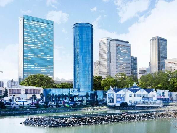 A cityscape with modern high-rise buildings, a waterfront area, and a small house-like structure with a sign. - Sky Tower Hotel (Batumi)