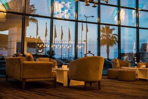 A modern lounge area with comfortable seating and large windows offering views of the cityscape. - Sky Tower Hotel (Batumi)
