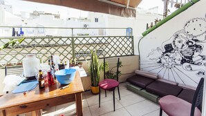 A balcony with a wooden table, chairs, and a mural. - Granny's Inn - Hostel (Sliema)