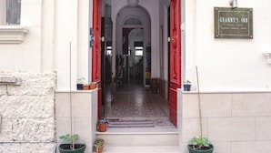 A hotel entrance with a red awning, a plaque reading "GRANNY'S INN," and potted plants at the entrance. - Granny's Inn - Hostel (Sliema)