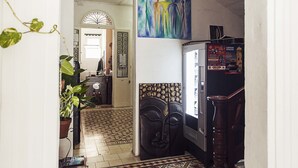 A hallway with a tiled floor, a refrigerator, and a painting on the wall. - Granny's Inn - Hostel (Sliema)