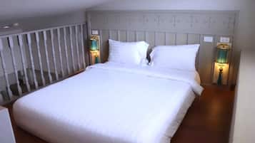 A neatly made bed with white linens in a room with a wooden headboard and two wall-mounted lamps.