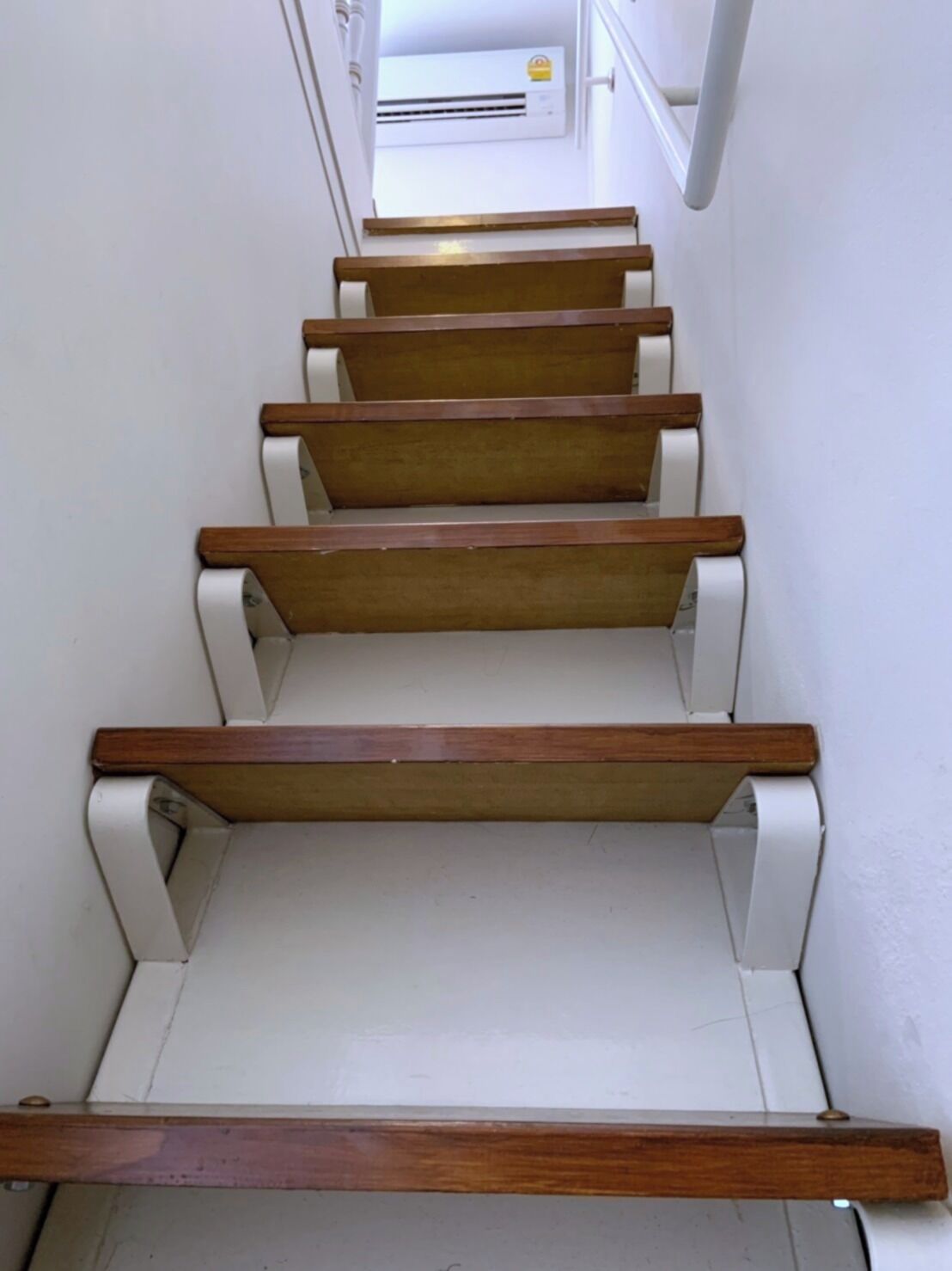 A staircase with wooden steps and white handrails, leading to an upper floor.