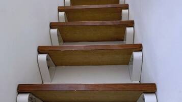 A staircase with wooden steps and white handrails, leading to an upper floor.