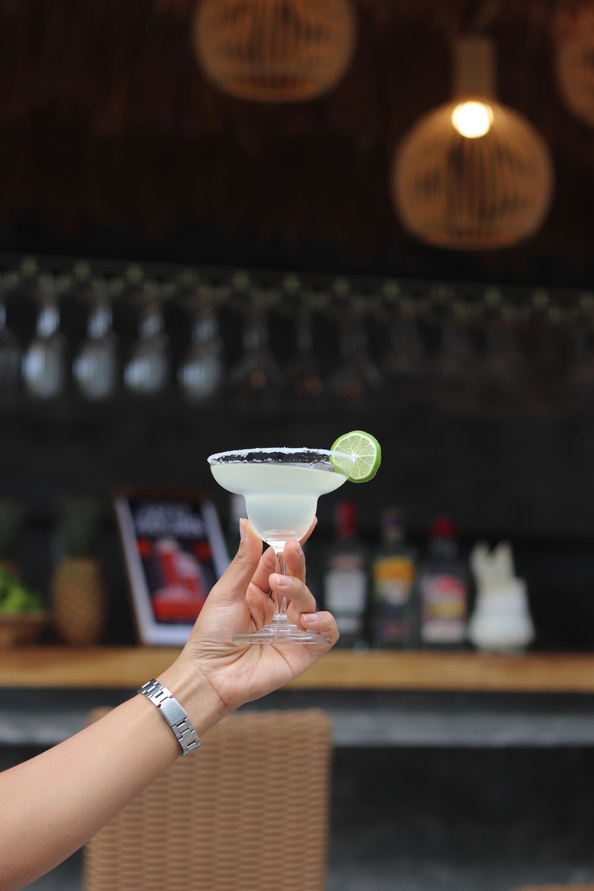 Una mà subjectant un got de margarita amb una taronja agra.