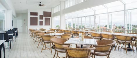 A spacious indoor dining area with high ceilings, large windows, and a view of the cityscape.