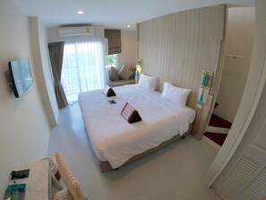 Habitación de hotel con una cama grande, televisión, ventana con cortinas y aire acondicionado instalado en la pared.