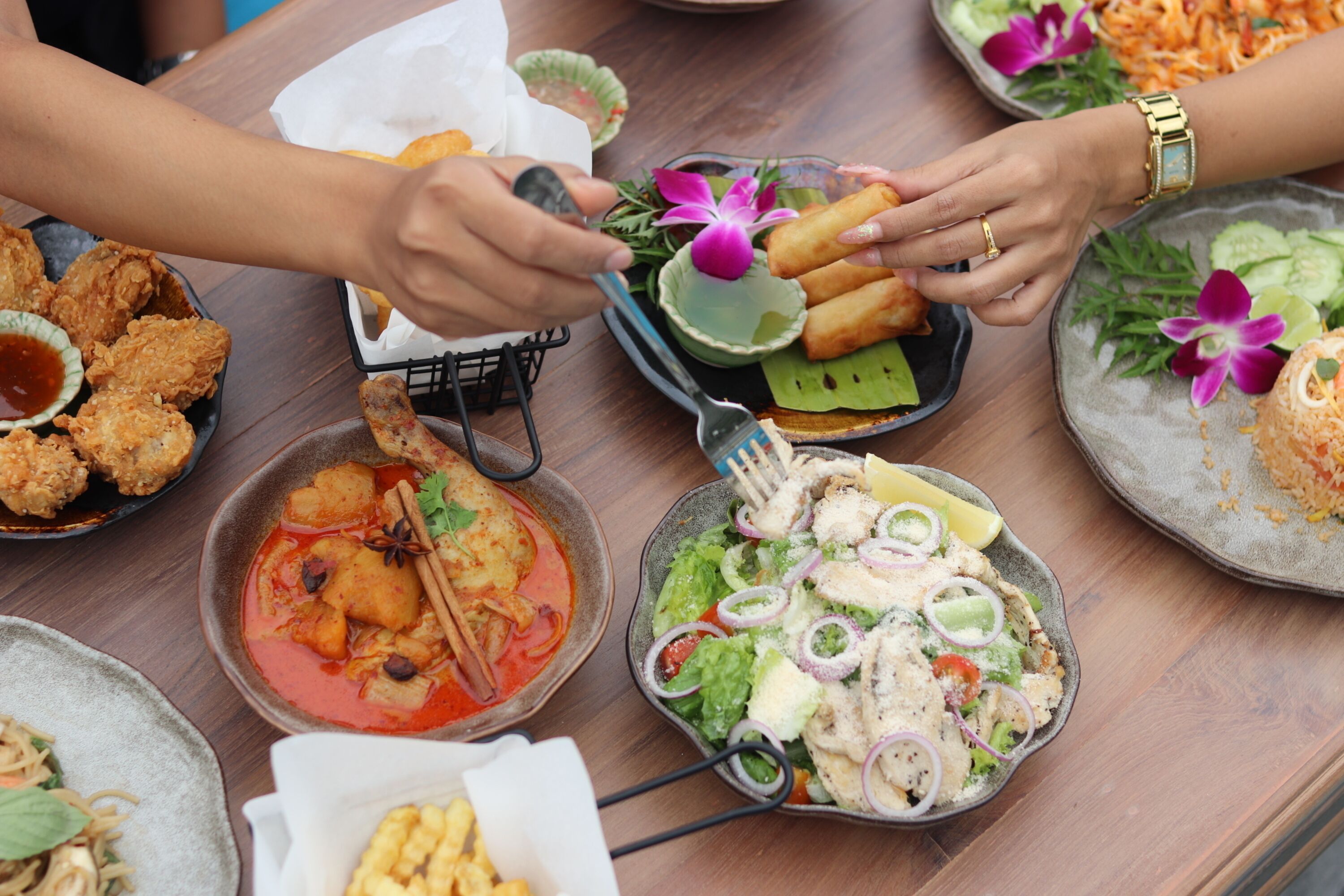 Ein Tisch mit verschiedenen Speisen, darunter frittierte Gerichte, eine Suppenschüssel und ein Salat mit Gemüse.