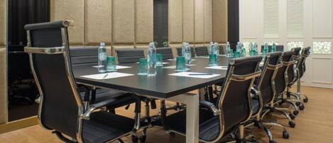 A conference room with a long table, black chairs, and water bottles.