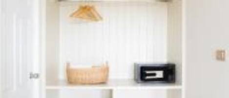 A white closet with open shelves, a hanging basket, and a black storage box.