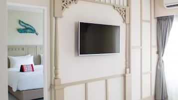 A hotel room with a bed, a flat-screen TV mounted on a decorative wall, and a window with curtains.