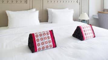 A hotel room with a large bed, white bedding, a decorative feather on the wall, and a lamp on the side.