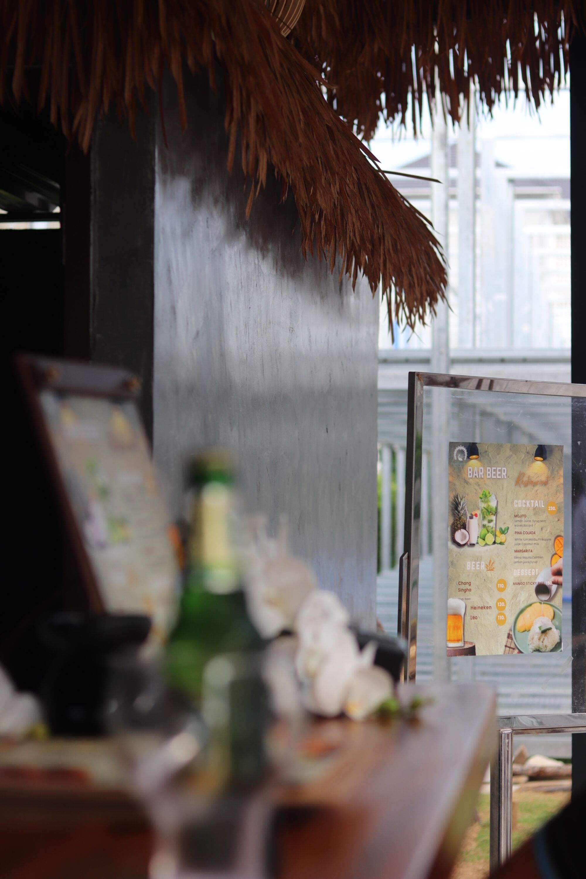 A bar area with a menu board displaying drinks and a bottle of beer on the counter.