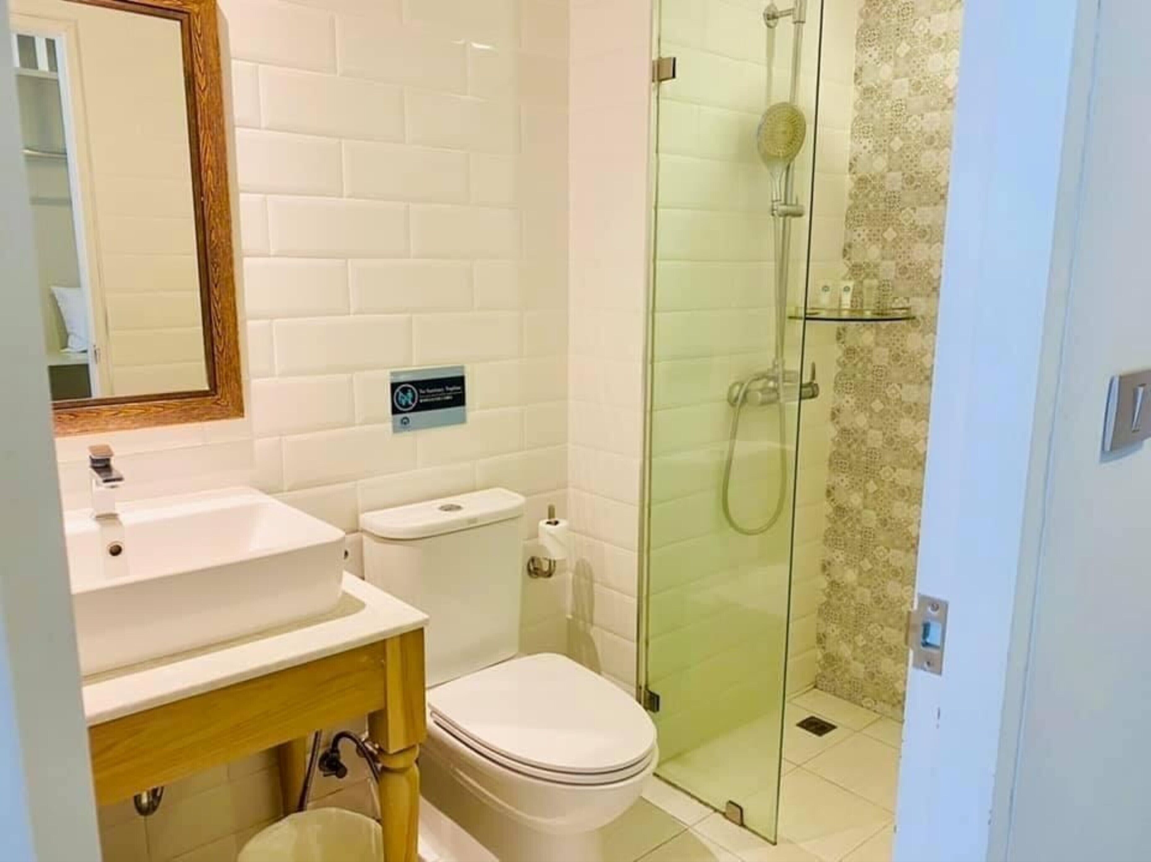 Une salle de bain avec un lavabo blanc, des toilettes et une douche fermée par des parois en verre.