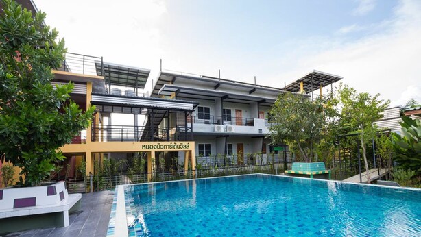 Un hôtel moderne doté d’une piscine, d’un espace extérieur aménagé et d’une végétation luxuriante.