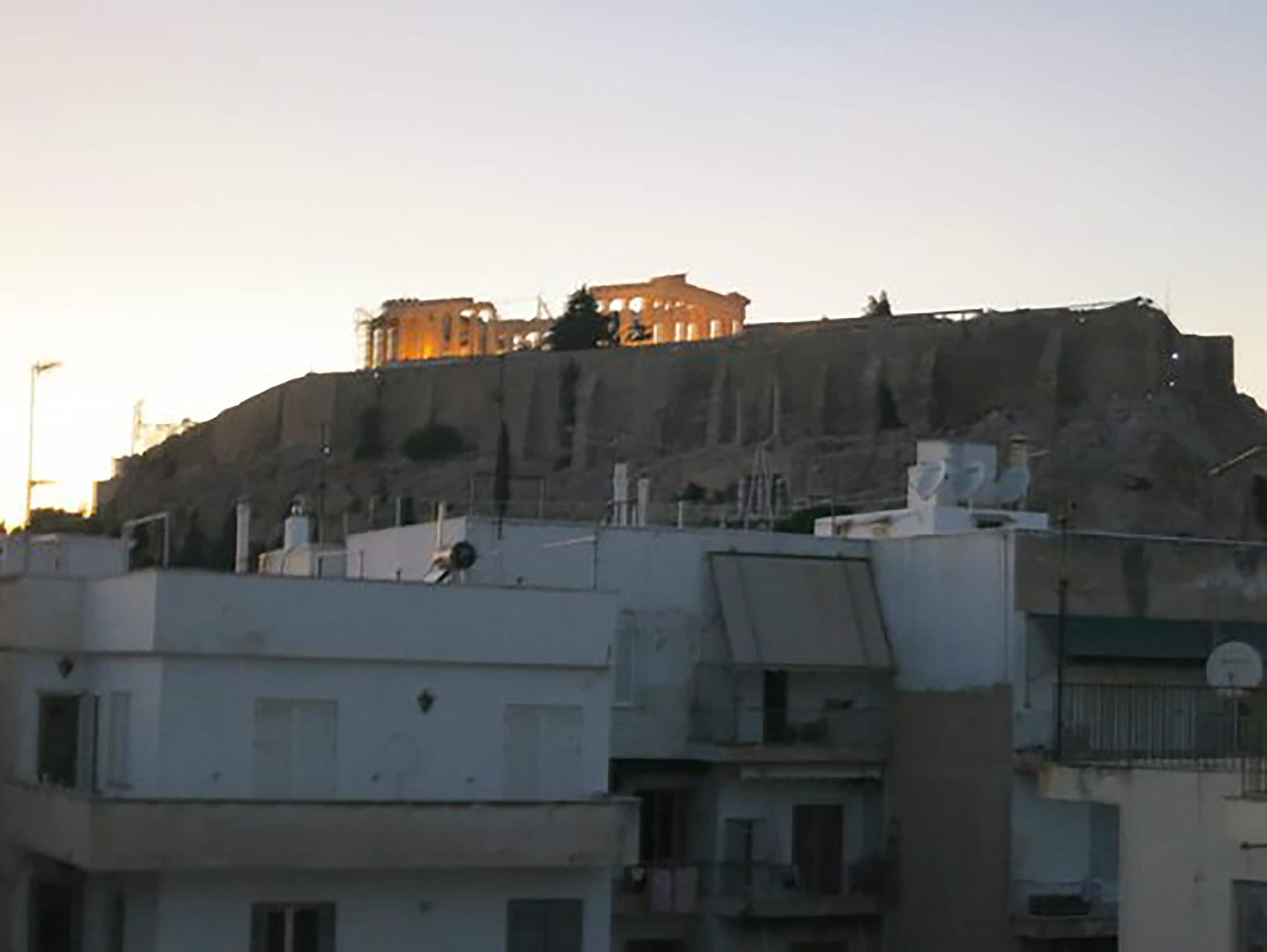 Un bâtiment doté d’un toit plat et de nombreuses fenêtres, entouré d’autres constructions.