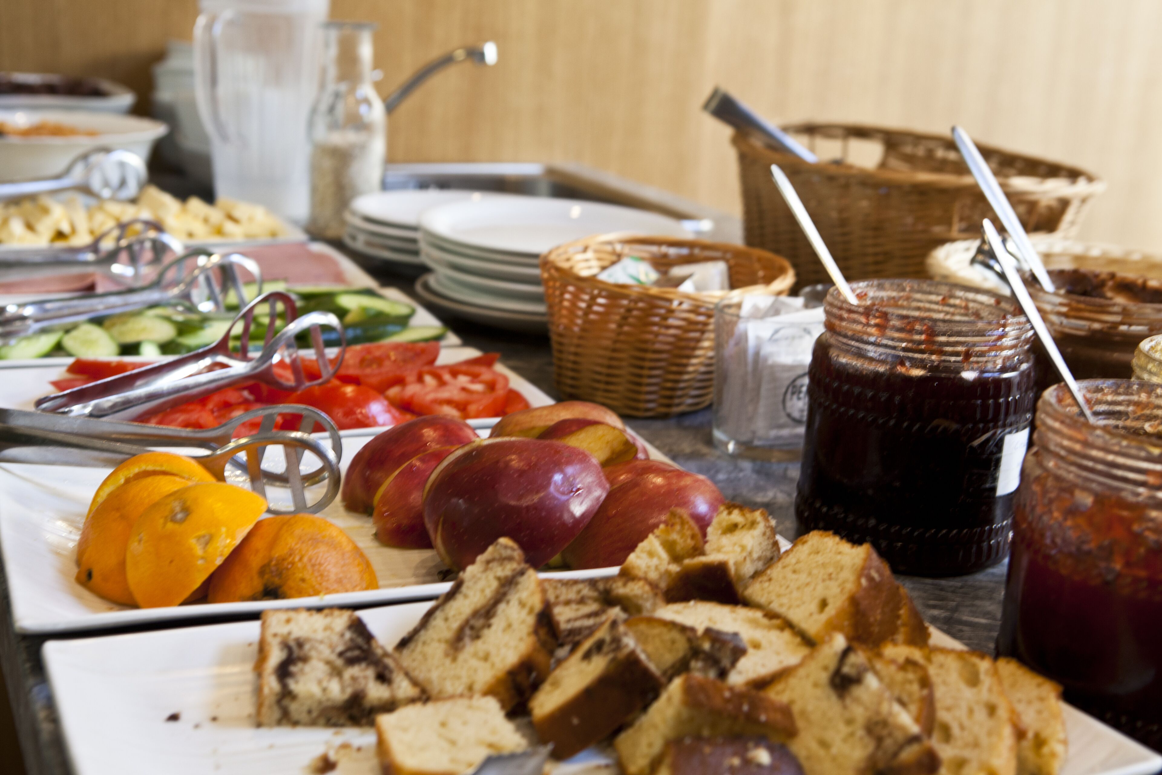 Buffet com diversas opções de comida, incluindo frutas, pães e acompanhamentos.