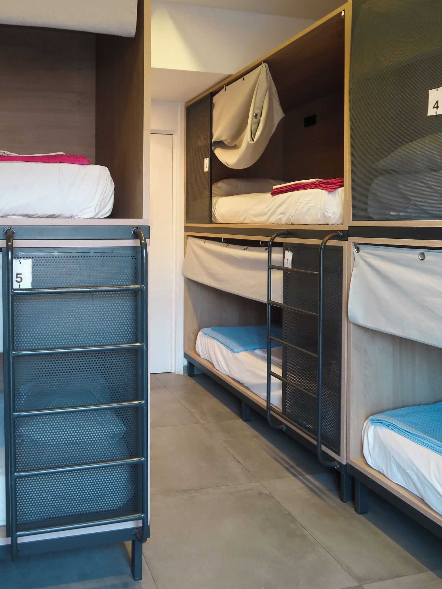 A row of bunk beds with metal railings, each bed has a number tag.
