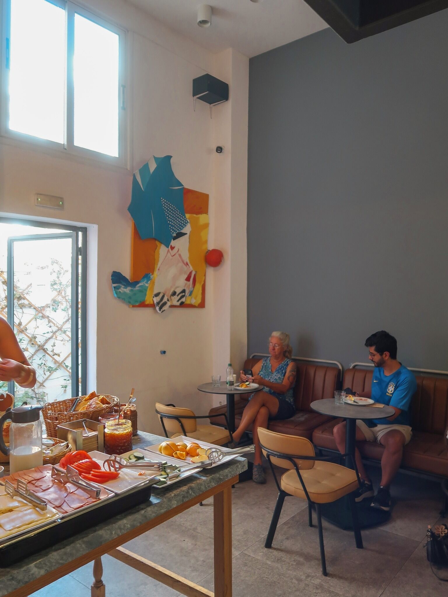 Un espace repas comprenant une table de buffet, des chaises et un mur orné d’œuvres d’art abstraites.