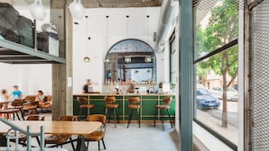 A restaurant with a bar area, seating, and a view of the street.