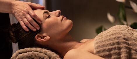 A person receiving a head massage in a spa setting.