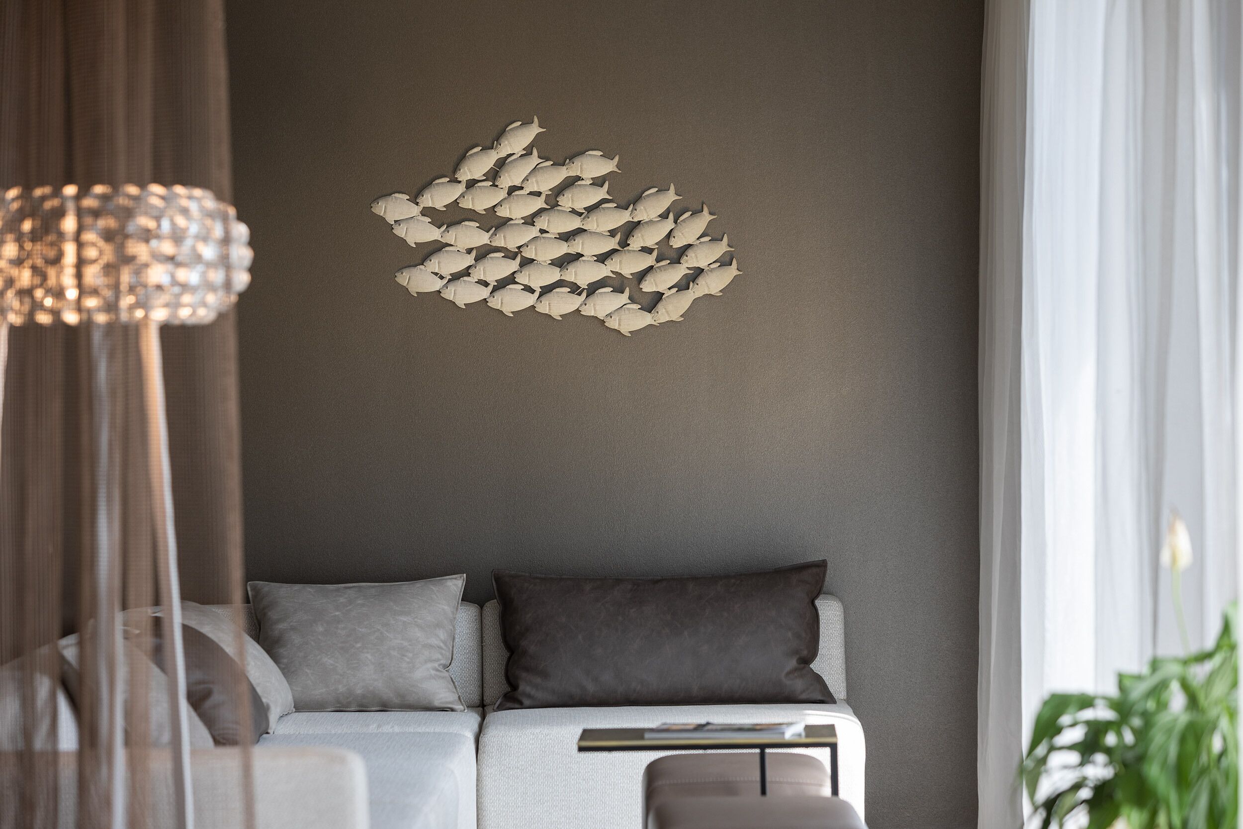 Ein modernes Wohnzimmer mit einer Couch, einer Wanddekoration und einer Pendelleuchte.