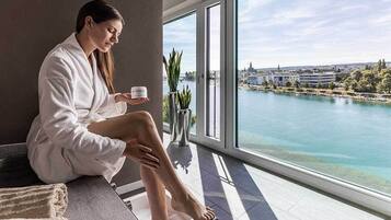 Eine Person sitzt am Fenster mit Blick auf ein Gewässer und Gebäude.