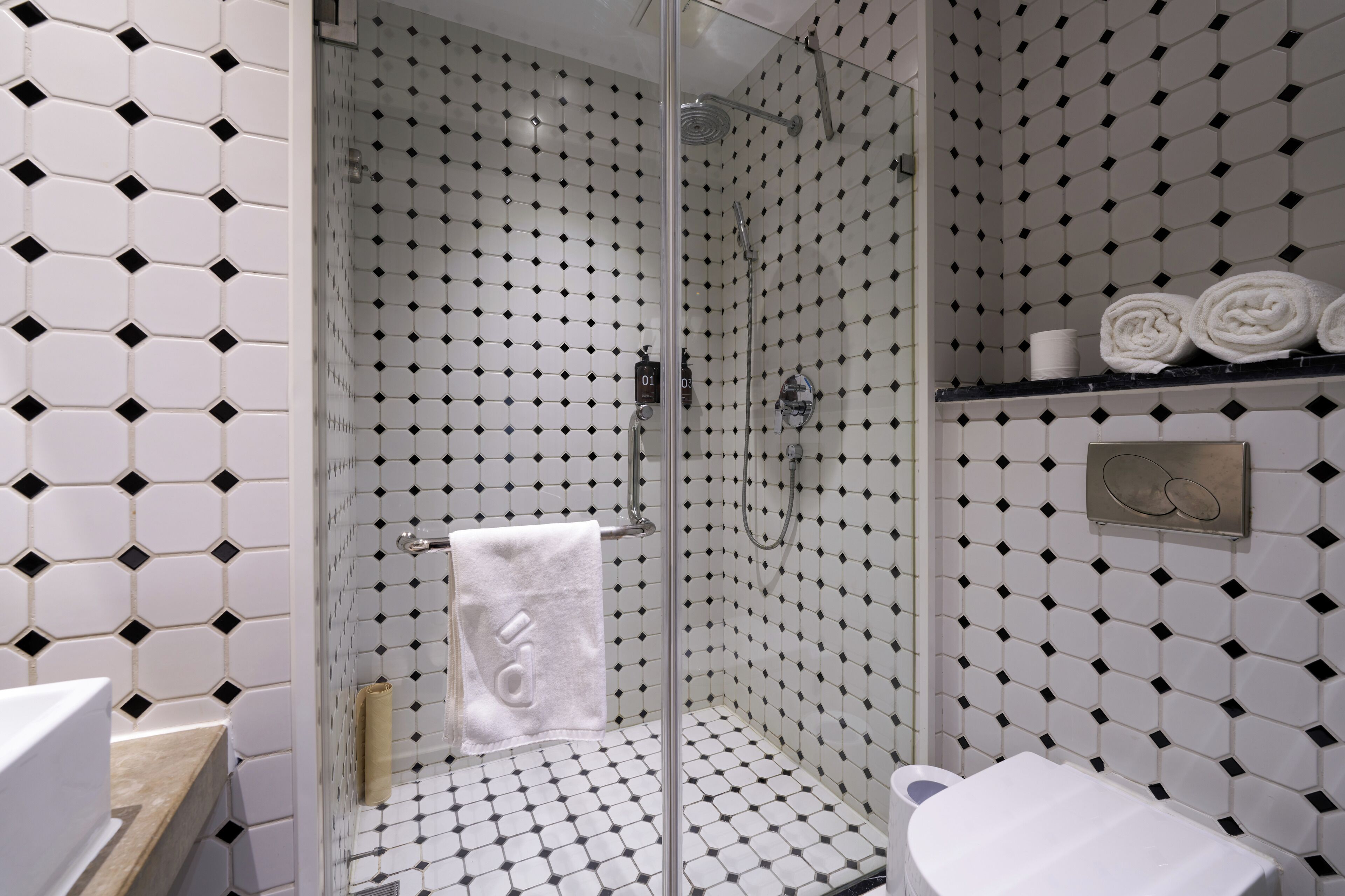 Une salle de bain équipée d’une douche, de toilettes et d’un porte-serviettes avec des serviettes pliées.