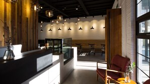 Decoração moderna com balcão de recepção, área de estar e iluminação pendente.