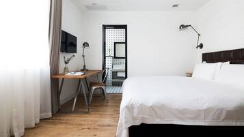 Ein Hotelzimmer mit einem Holztisch, einem Bett, einem Fernseher und einem durch eine offene Tür einsehbarer Badezimmer.