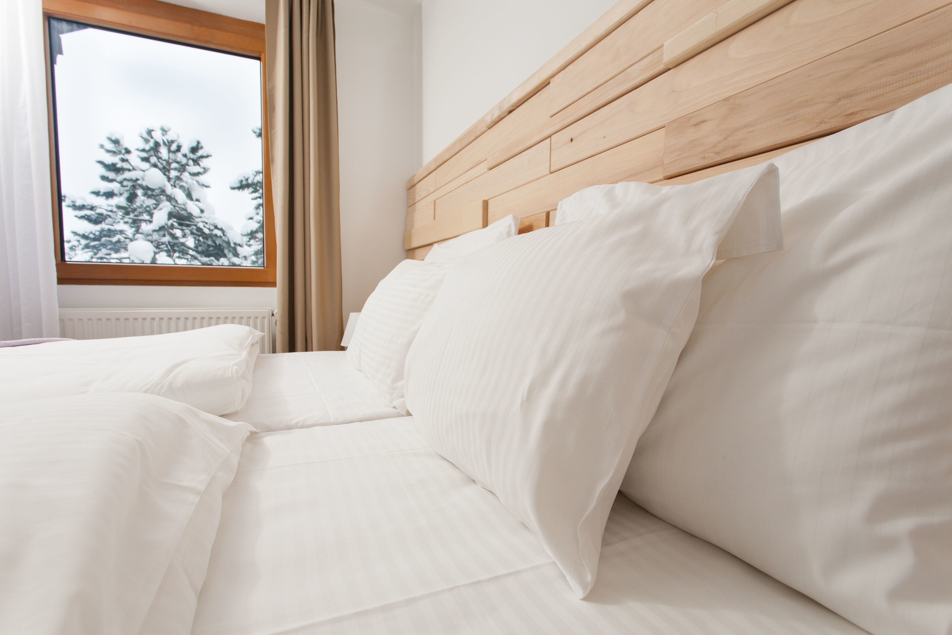 Una cama bien hecha con sábanas blancas y cabecera de madera.