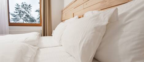 Una cama bien hecha con sábanas blancas y cabecera de madera.