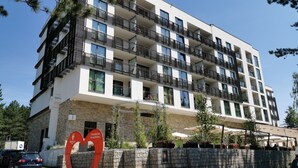 A multi-story hotel with balconies, a stone facade, and outdoor seating areas. - Hotel Palisad (Zlatibor)