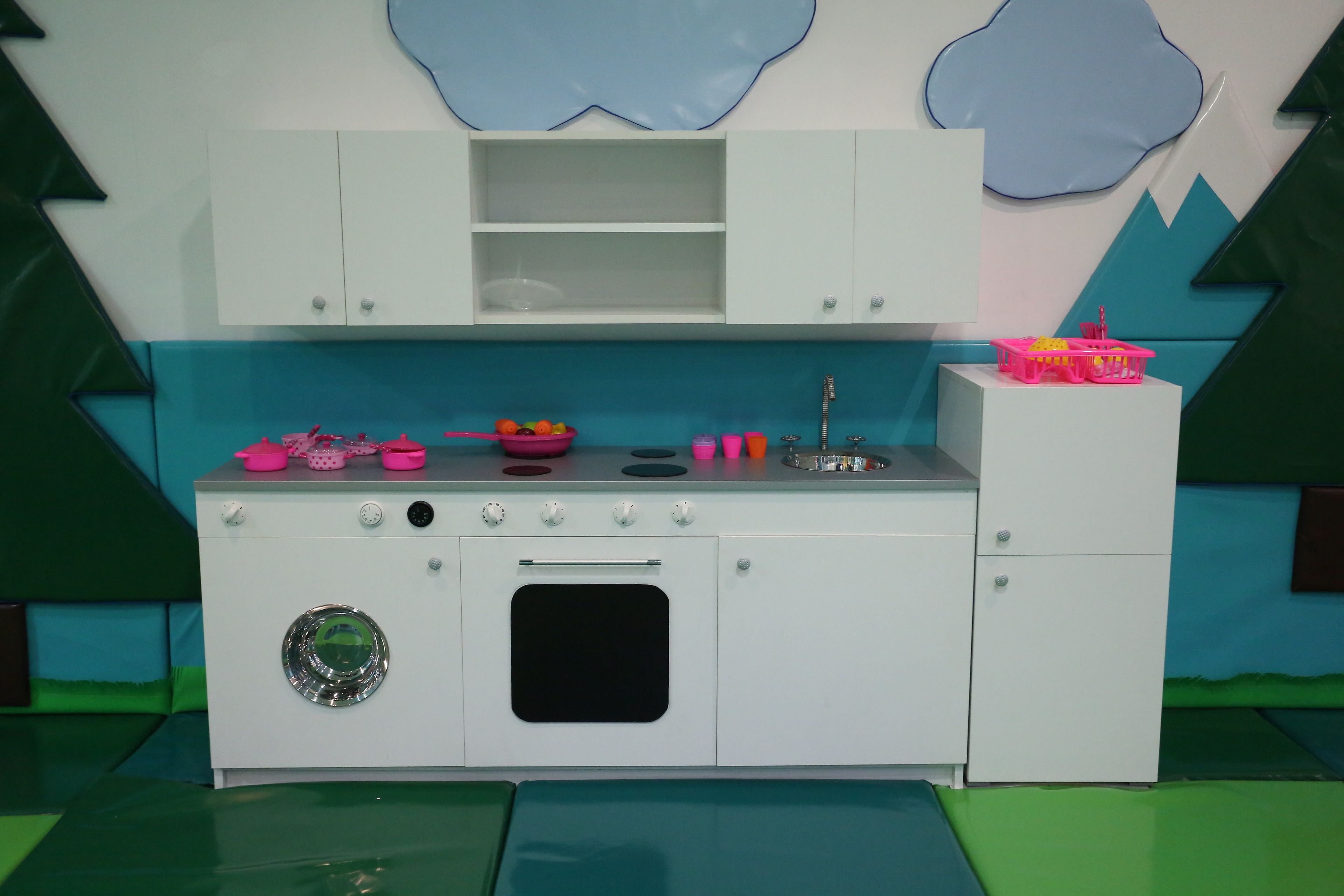 A children's play kitchen with a sink, stove, and cabinets.