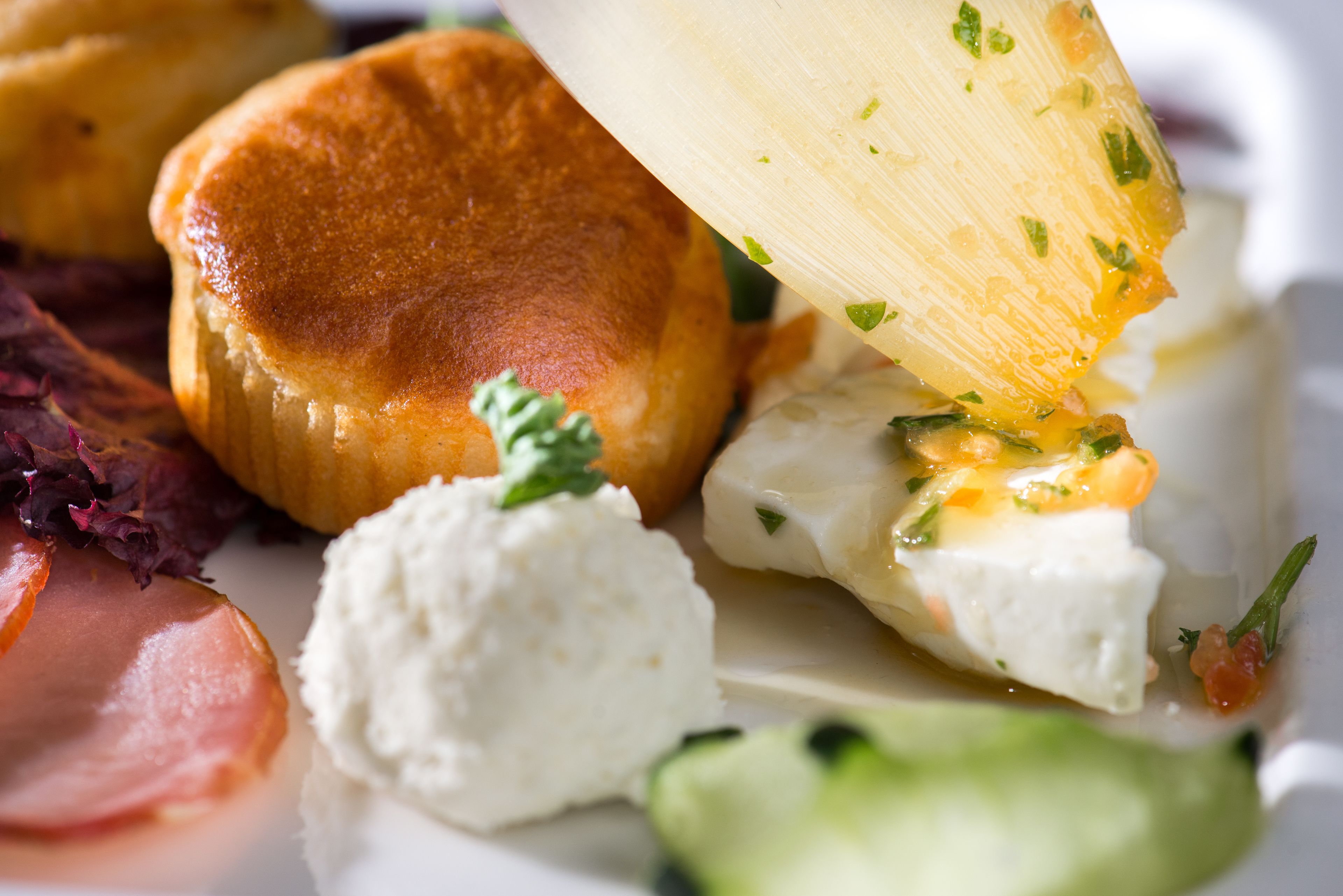 A plate with various food items including a piece of bread, a slice of cheese, and some vegetables.