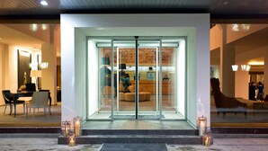 A hotel entrance with a glass door, a reception desk, and a seating area visible through the glass. - Hotel Palisad (Zlatibor)