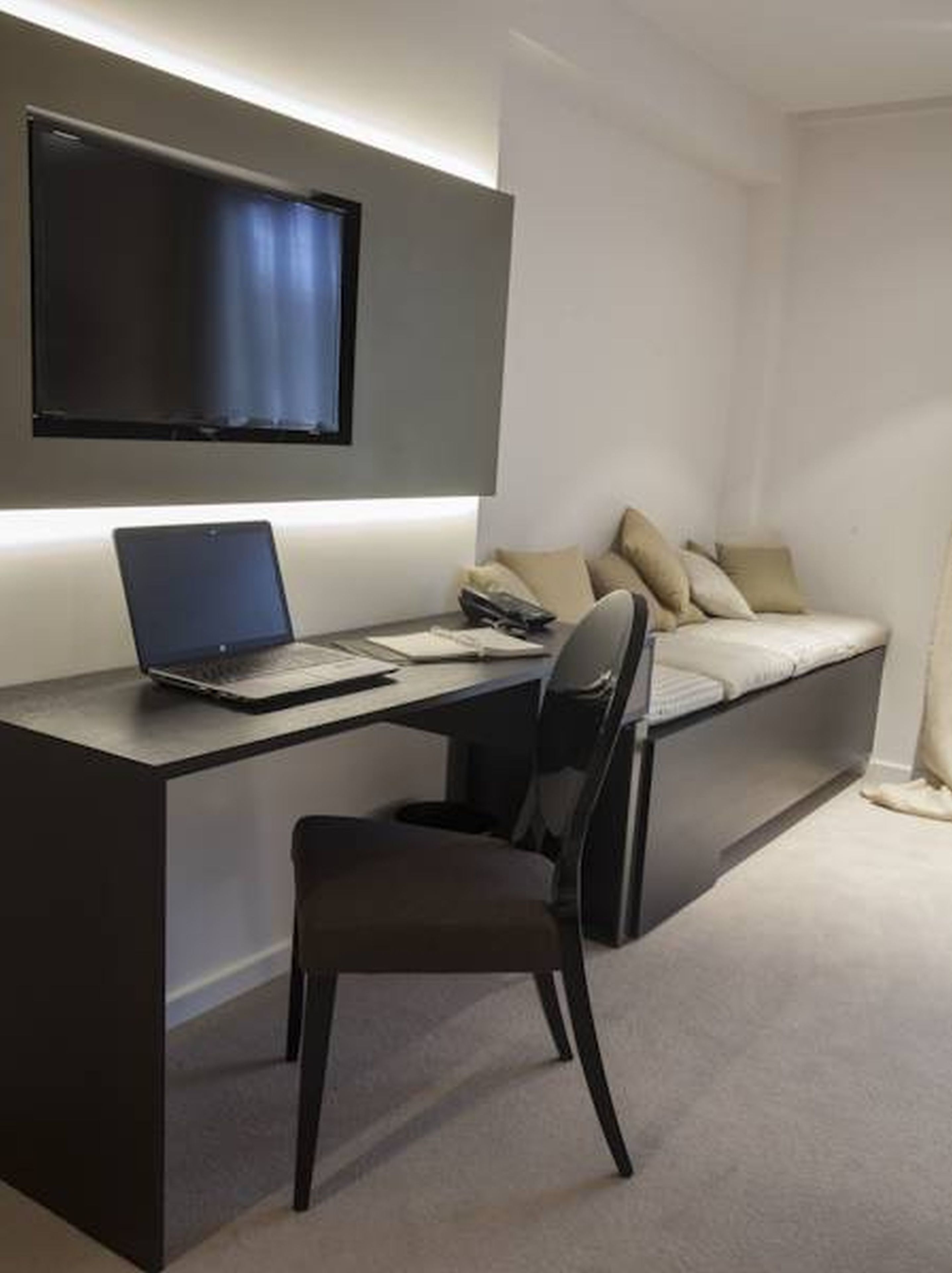 A modern bedroom with a desk, chair, and a bed with pillows.