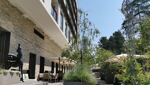 A courtyard with outdoor seating, a large planter, and a brick building facade. - Hotel Palisad (Zlatibor)