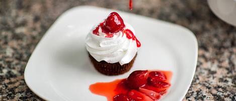 A dessert on a white plate with strawberries and a red sauce.
