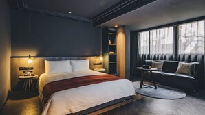 A modern hotel room with a large bed, bedside tables, a reading area with a sofa and a small table, and a large window with curtains. - Atour Hotel Jing'an The Drama Shanghai (Shanghai)