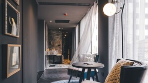 A modern hotel room with a round table, a comfortable chair, and a view of the city through large windows. - Atour Hotel Jing'an The Drama Shanghai (Shanghai)