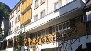 A multi-story hotel with a white facade, multiple balconies, and a staircase with a wooden railing.