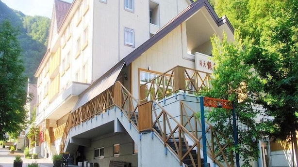A multi-story hotel with a modern design, featuring a prominent staircase and a balcony.