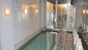 A swimming pool with a tiled floor, a stone border, and a row of sinks with soap dispensers.
