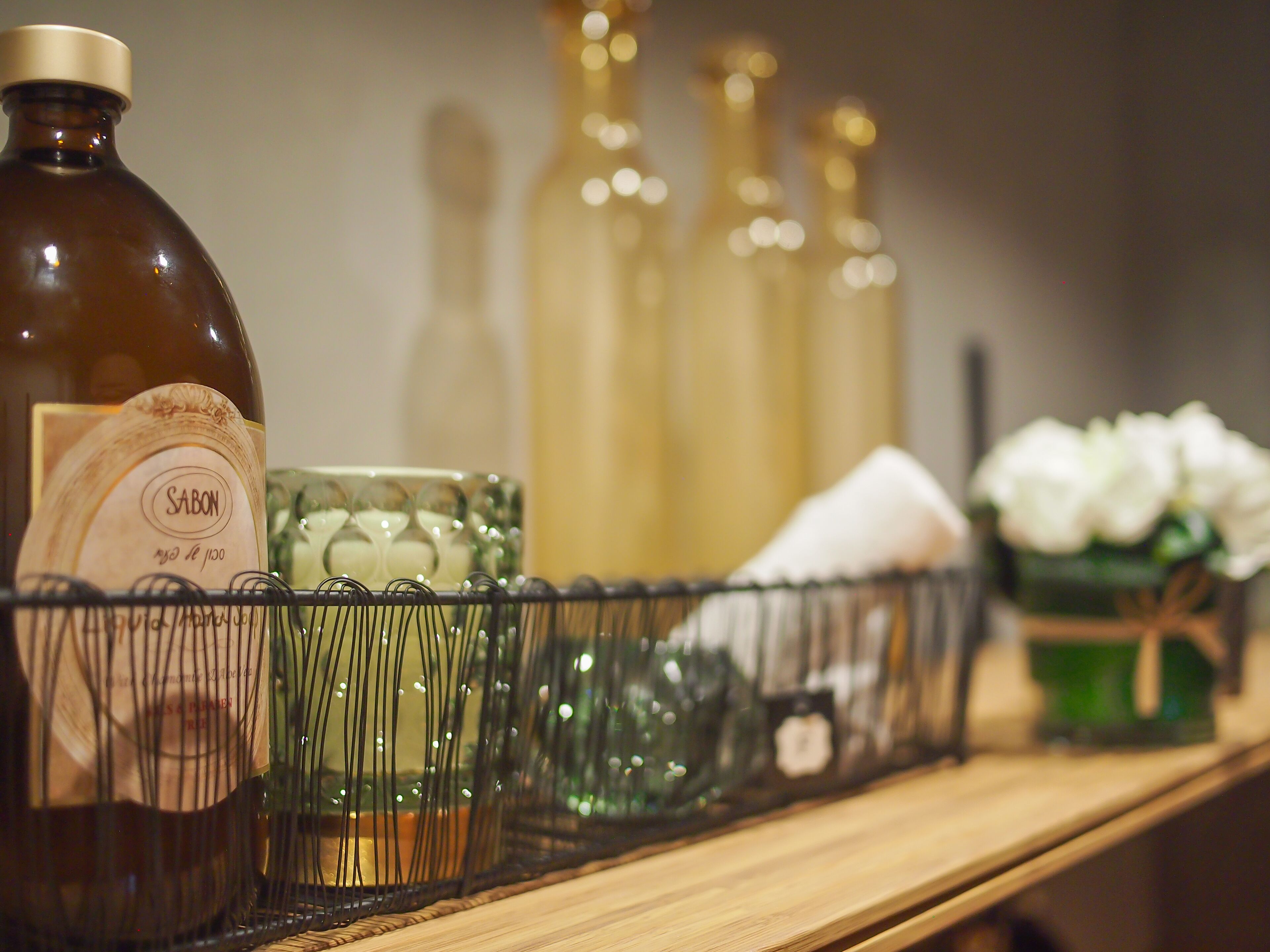 A shelf with various bottles and containers, including a large brown bottle labeled "SABON" and several clear glass bottles.