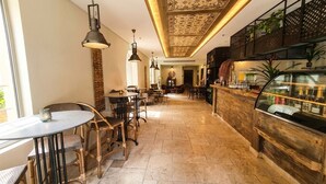 A restaurant with a bar area, tables, chairs, and a decorative ceiling.